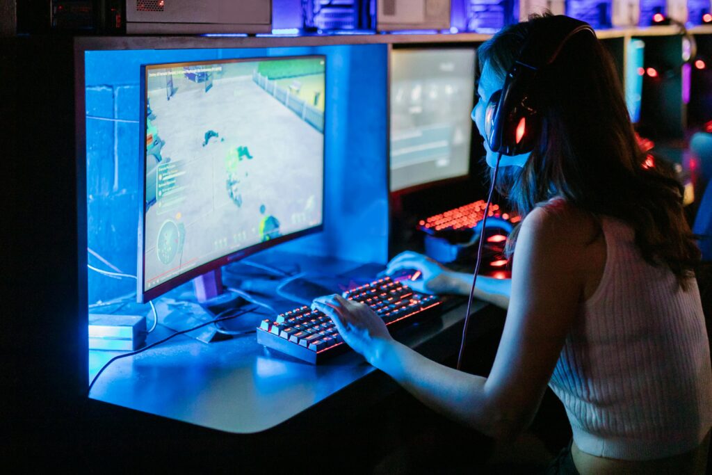 Woman enjoying a vibrant gaming session at a computer setup with a mechanical keyboard.