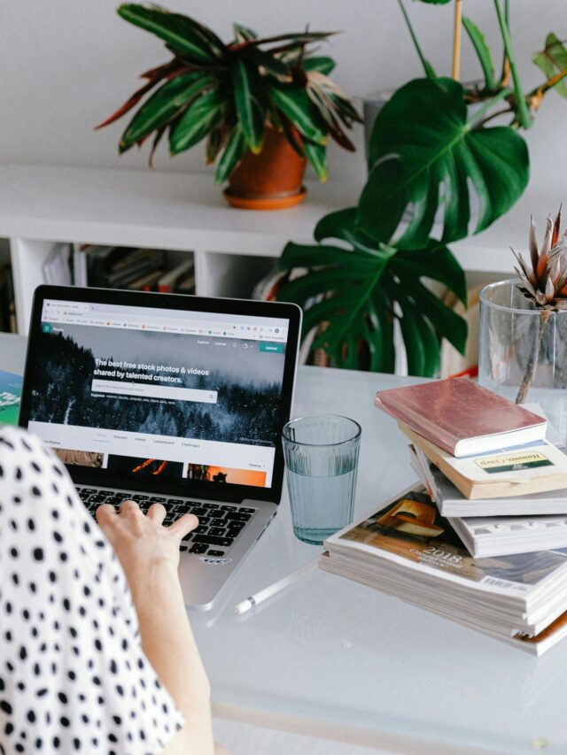 A woman working from home on her laptop surrounded by plants and books for a cozy office feel.